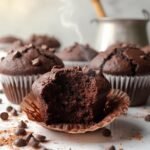 "Close-up of freshly baked double chocolate muffins with chocolate chips on a clean white marble surface"