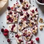 "Overhead view of high-protein frozen Greek yogurt bark with mixed berries, nuts, chocolate on a marble countertop"
