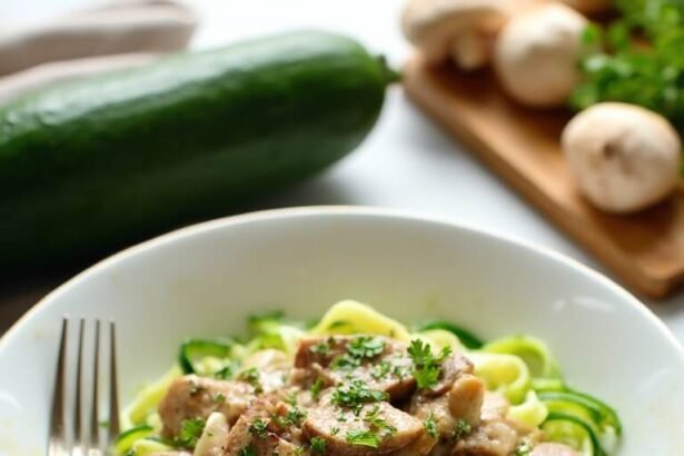 "Creamy beef stroganoff with zucchini noodles in a white bowl on marble countertop, with whole zucchini, mushrooms, and herbs in background"