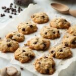 Freshly baked keto chocolate chip cookies made with almond and coconut flour on a marble countertop, with baking ingredients in the background.