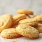 "Freshly baked keto sugar cookies with almond and coconut flour on a clean white marble background, subtly steaming and glowing under soft natural light."