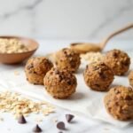 "No-bake protein energy balls with oats, peanut butter, and chocolate chips on a marble surface"