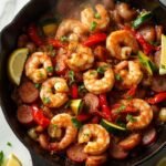 "Cajun shrimp and sausage stir-fry with bell peppers and zucchini in a sizzling skillet on a white marble background"