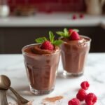 "Chocolate mousse with fresh raspberries on a marble countertop in a modern kitchen setting"