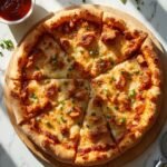 "Overhead shot of keto BBQ chicken pizza with golden fathead crust, melted cheese and green chives on a white marble surface"