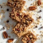 "Keto granola bars with almonds, pecans, and chocolate chips on a clean white marble background"