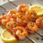 "Grilled keto lemon butter shrimp skewers on a white ceramic platter with parsley and lemon wedges, shot from a 45-degree angle in cinematic lighting"