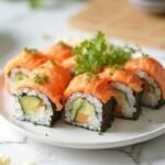 "Freshly sliced keto sushi rolls with salmon, cauliflower rice, avocado, and cucumber on a white ceramic plate"