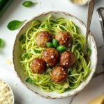 "Keto-friendly spaghetti with zucchini noodles and meatballs, garnished with fresh parmesan and basil leaves, displayed on a clean white background with key ingredients scattered around."