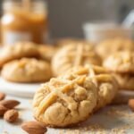 "Freshly baked soft almond flour peanut butter cookies with criss-cross pattern on a clean marble surface"