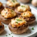 "Golden-brown low-carb stuffed mushrooms with Italian sausage and cream cheese filling on a white serving platter"